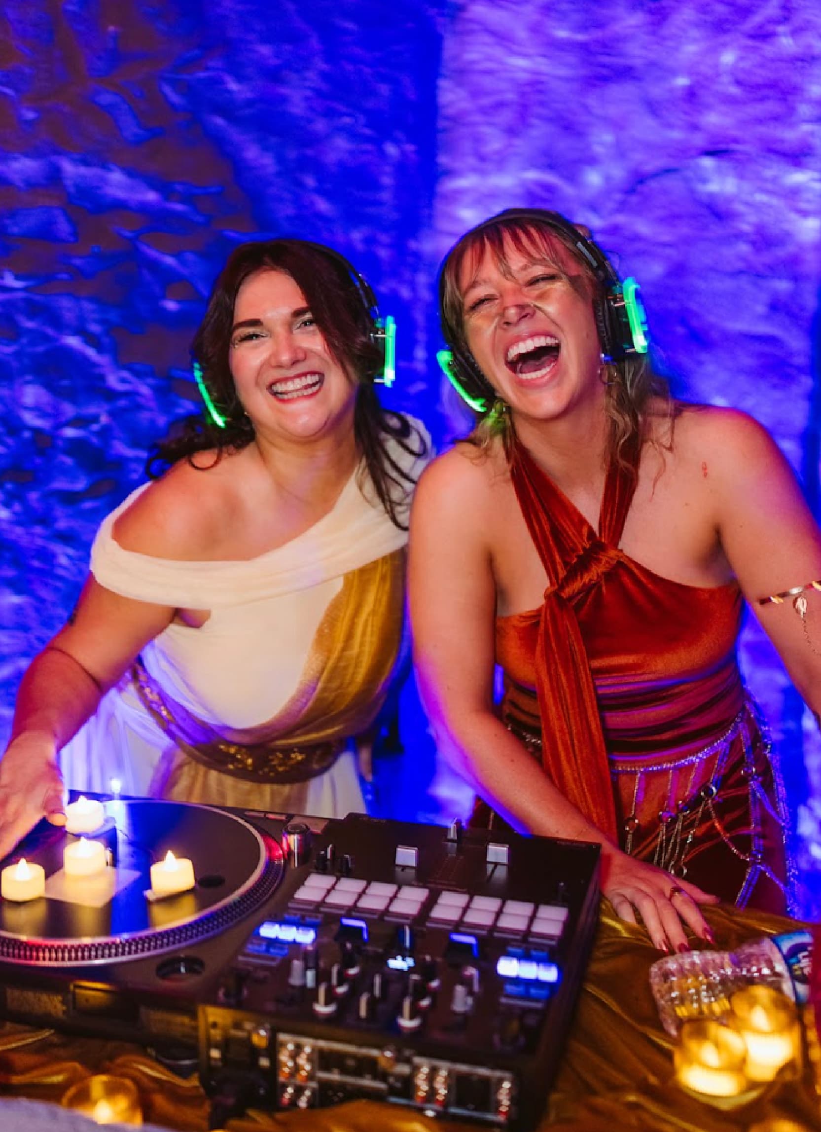 Two women smiling and wearing headphones in a dj booth