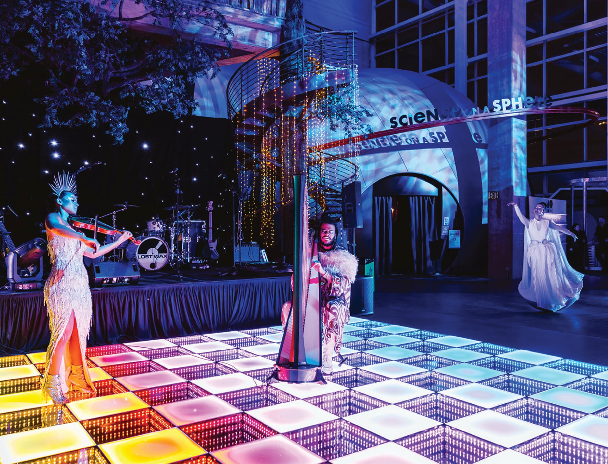 Three musicians and dancers are on a rainbow disco floor