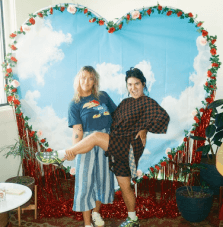 Girls posing in front of a heart photo back drop