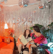 Couple posing in front of balloons '1994' and disco balls